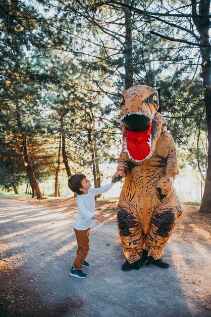 Vader en zoon spelen in het park, met een dinosaurus kostuum, plezier maken met het gezin buiten