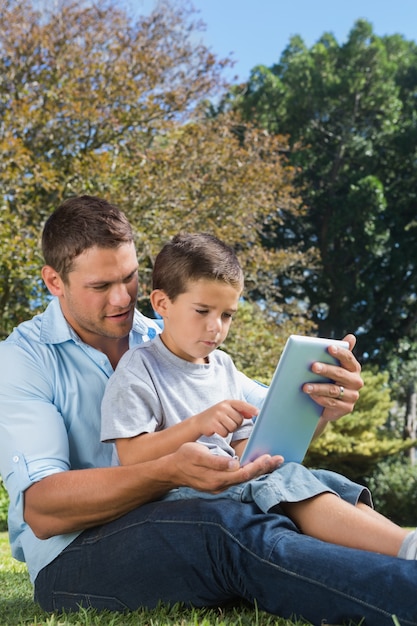 Vader en zoon spelen met een tablet-pc in een park