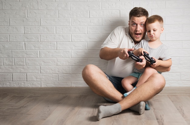 Foto vader en zoon spelen met hun controllers met kopie ruimte