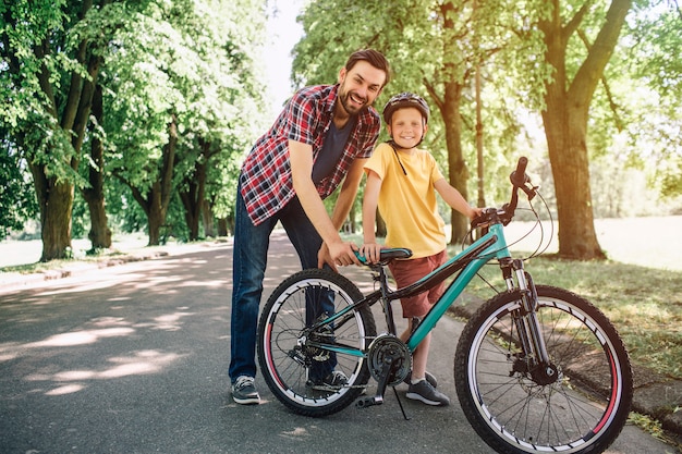 Vader en zoon staan en houden een fiets vast