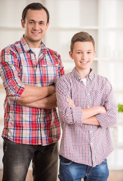 Foto vader en zoon staan samen en glimlachen naar de camera.