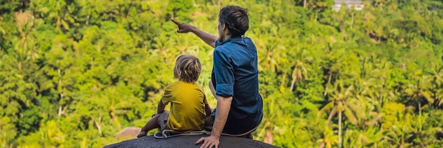 Vader en zoon toeristen op een steen over de jungle reizen met kinderen concept wat te doen met kinderen