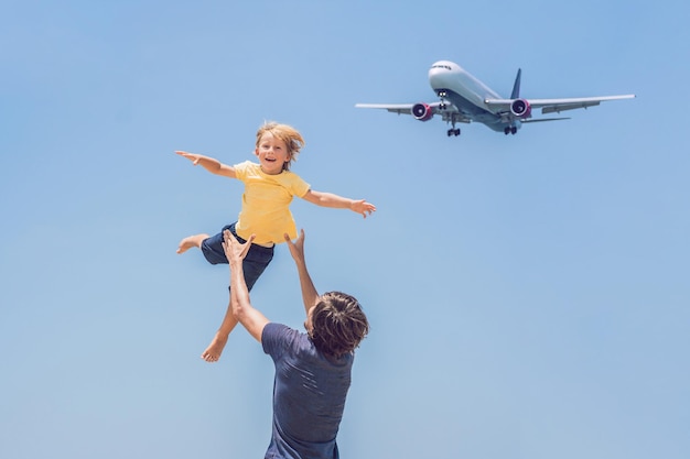 Vader en zoon vermaken zich op het strand en kijken naar de landende vliegtuigen. Reizen op een vliegtuig met kinderen concept.