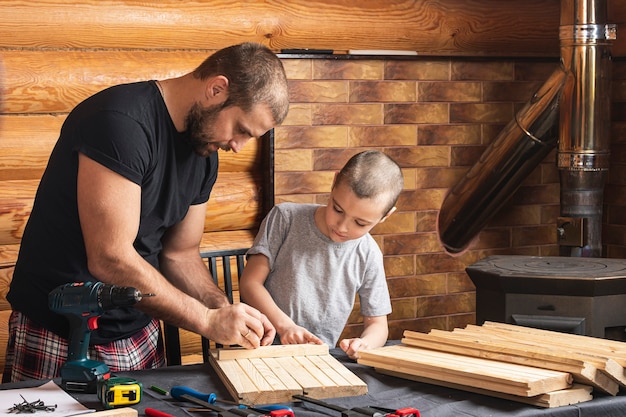 Vader en zoon werken aan een houten product en maken markeringen voor bevestiging