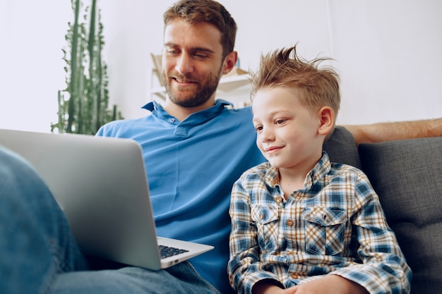 Vader en zoon zittend op de bank en kijken naar iets op laptop