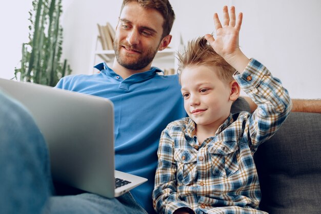 Vader en zoon zittend op de bank en kijken naar iets op laptop