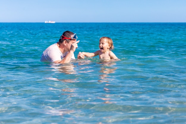 Vader en zoontje plezier zwemmen en spelen samen in zeewater op zomervakantie