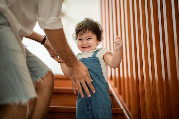 Vader helpt kinderen baby om kinderjaren familie mensen te lopen met kleine schattige peuter kind zoon gelukkig leren in de eerste stap met steun samen van vader thuis