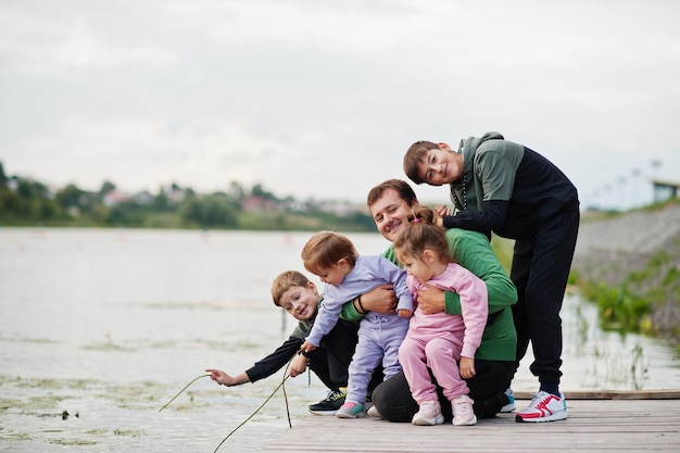 Vader houdt van vader met vier kinderen buiten op de pier Sport grote familie brengt vrije tijd buitenshuis door