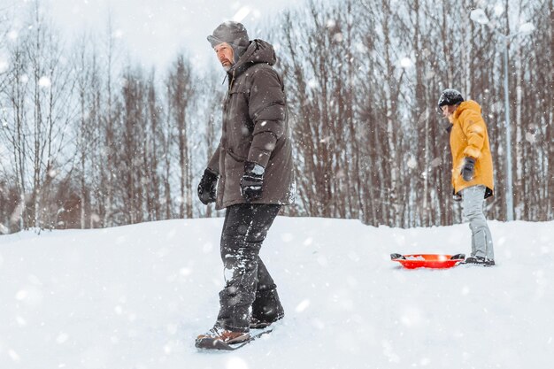 Vader leert zijn dochter sneeuwschaatsen tijdens een familiewandeling in het winterpark in de frisse lucht