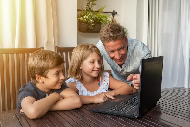 Vader leert zijn kinderen een laptop te gebruiken Nieuwe technologieën voor schoolhuiswerk en dagelijkse taken