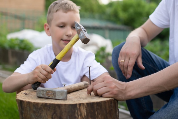 Vader leert zijn zoon spijkers in een boom te slaan