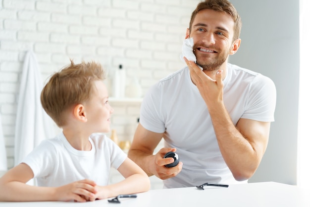 Vader leert zijn zoontje hoe hij het gezicht in de badkamer moet scheren