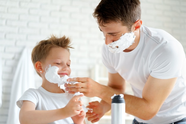 Vader leert zijn zoontje hoe hij het gezicht moet scheren