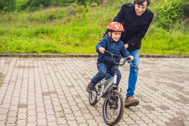 Vader leert zoon fietsen in het park.