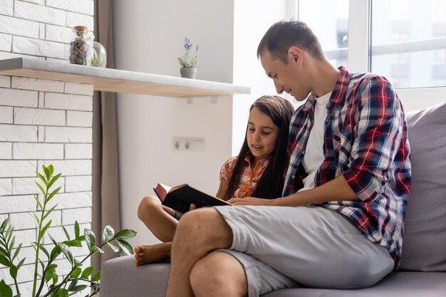 Vader leest thuis de Bijbel voor aan zijn dochtertje