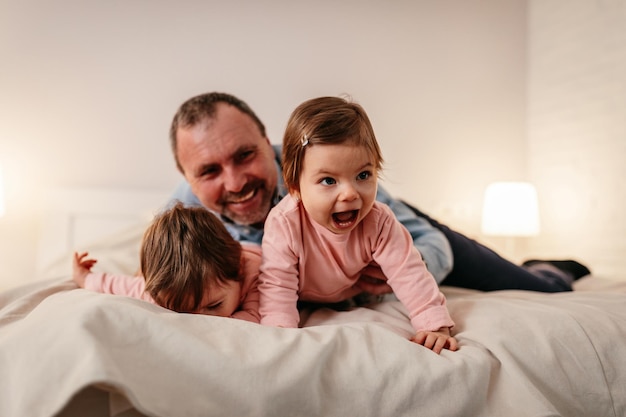 Vader liggend op bed met twee babymeisjes