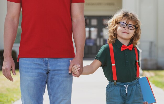 Foto vader loopt zoon naar school ouder en nerdleerling van basisschooljongen met rugzak