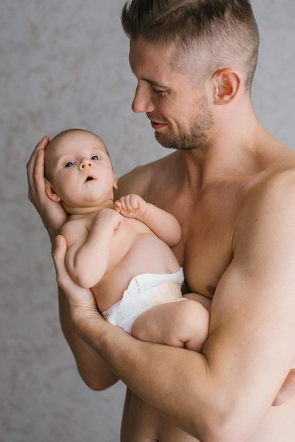 Vader met een baard houdt een pasgeboren baby in zijn armen op een grijze achtergrond Vakantieconcept Vaderdag