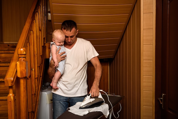 Vader met een kleine baby in haar armen gestreken linnen. Huishoudelijk werk doen