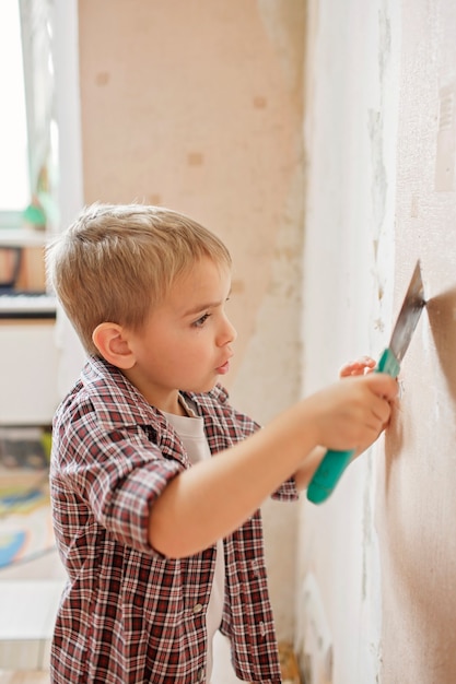 Vader met kind dat kamer samen repareert en behang samen loshangt