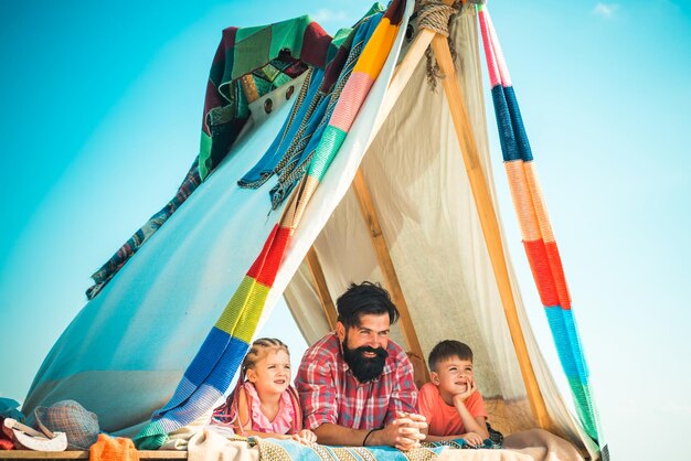 Vader met kinderen kinderen in tent. Zomer buiten vakantie. Familie samen spelen. Vaderdag.