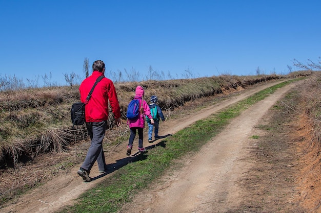 Vader met kinderen loopt langs het pad in laarzen en met rugzakken