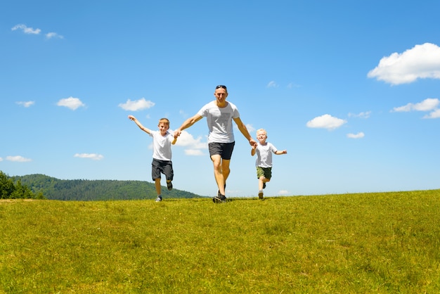 Vader met twee jonge kinderen die hand in hand op het groene gebied lopen