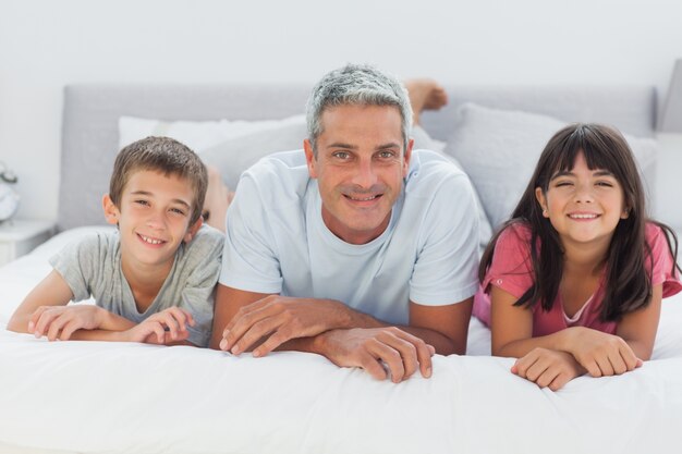 Vader met zijn kinderen liggend op bed