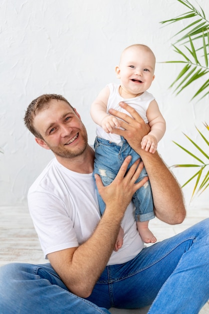 Vader met zoontje in zijn armen lachen op een witte achtergrond, gelukkig vaderschap en familie, vaderdag