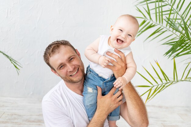 Vader met zoontje in zijn armen lachen op een witte achtergrond, gelukkig vaderschap en familie