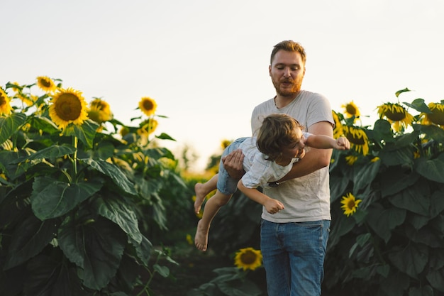 Vader met zoontje in zonnebloemenveld tijdens gouden uurtje vader en zoon zijn actief in de natuur