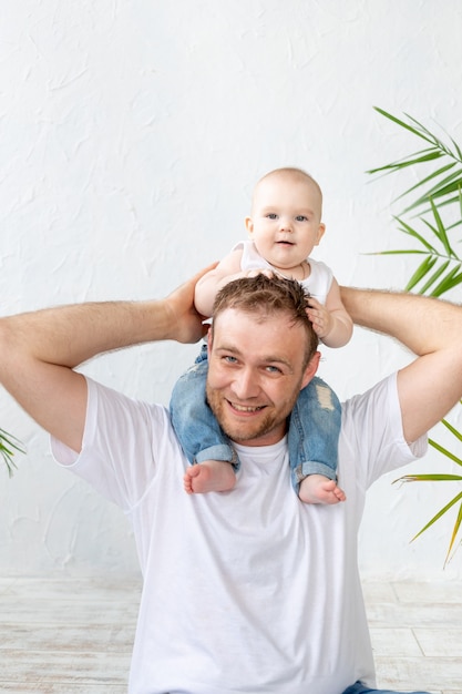 Vader met zoontje om zijn nek met plezier op een witte achtergrond, gelukkig vaderschap en familie