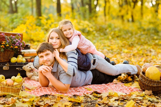 Vader, moeder en dochter hebben samen plezier tijdens een herfstpicknick op straat.