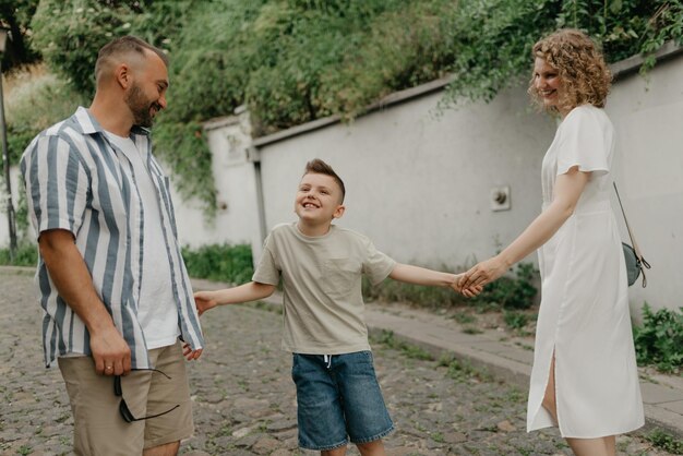 Vader, moeder en zoon houden elkaars hand vast op de groene geplaveide straat