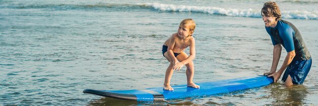 Vader of instructeur die zijn jaar oude zoon leert surfen in de zee tijdens vakantie of vakantiereizen
