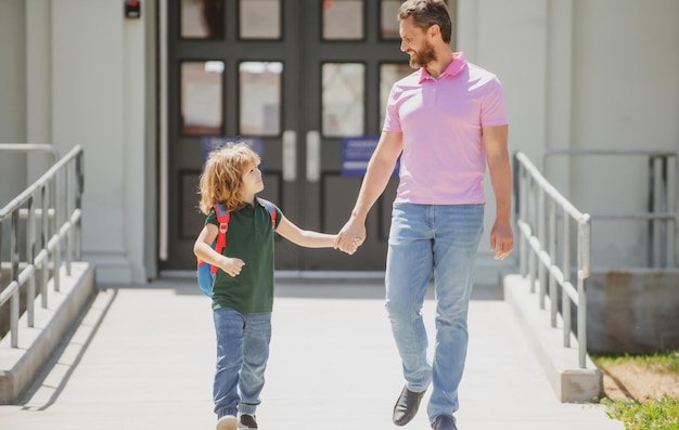 Vader ondersteunt en motiveert zoon Ouder brengt kind naar school Leerling van basisschool gaat met rugzak buiten studeren Ouder met kind voor schoolpoort