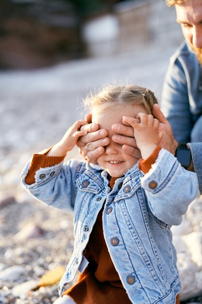 Vader sloot de ogen van het kleine meisje dat haar handpalmen op de close-up van zijn handen legde