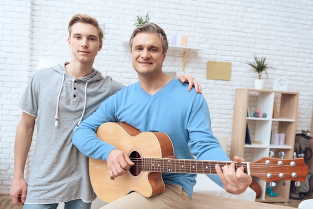 Vader speelt op gitaar en zijn zoon luistert