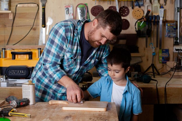 Vader timmerman en zoon jongen werken in de werkplaats Meester vader leert zijn zoon timmeren Continuïteit