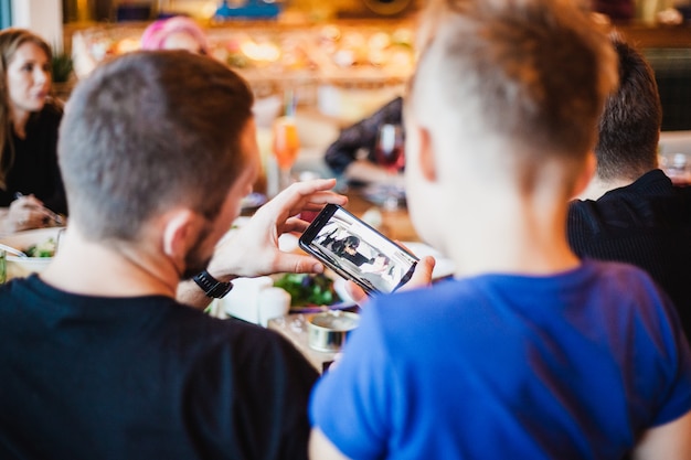 Vader toont zijn zoon een telefoon, een cartoon aan de telefoon voor het kind