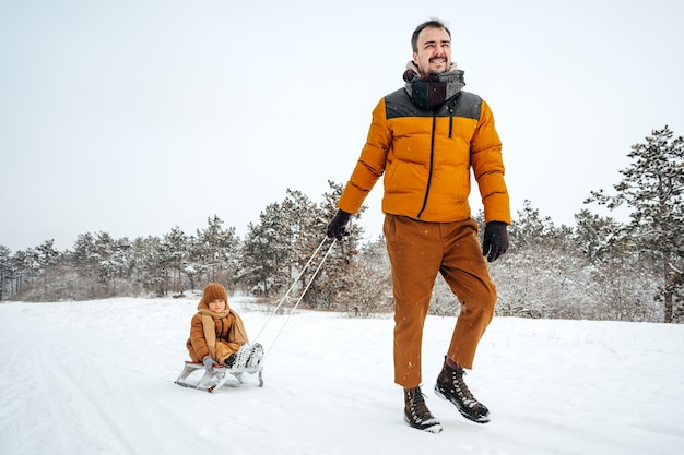 Vader trekt zoontje op slee in de winter