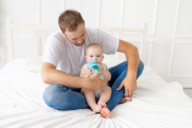 Vader voedt zoontje thuis uit een fles, gelukkig vaderschap, concept voor babyvoeding