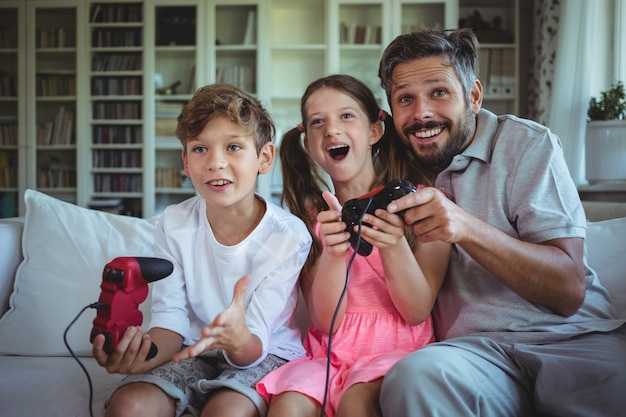 Vader zittend op de bank met zijn kinderen en het spelen van videogames