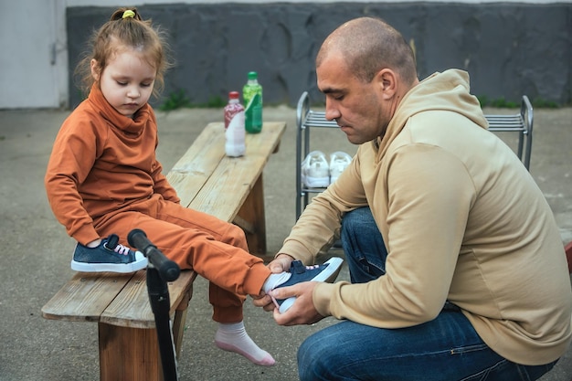 vader zorgt voor zijn dochtertje en helpt haar haar schoenen aan te trekken in het park