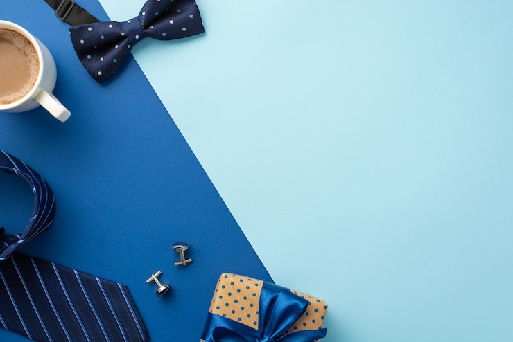 Vaderdag concept Bovenaanzicht foto van polka dot geschenkdoos met lint strik kopje koffie manchetknopen blauwe vlinderdas en stropdas op tweekleurige blauwe achtergrond met lege ruimte