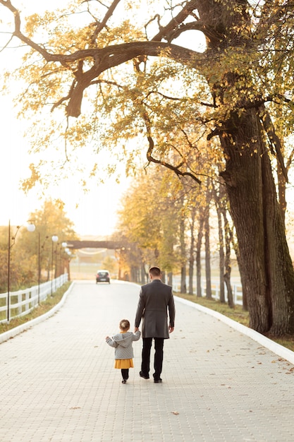 Vaderdag. Jonge gelukkige familievader en dochter tijdens een wandeling in het de herfstpark.