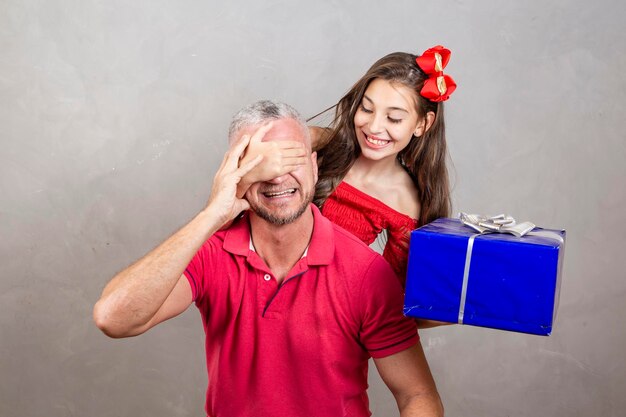 Vaderdag Kaukasische dochter bedekt de ogen van haar vader met een vaderdagcadeau Verrassing op Vaderdag