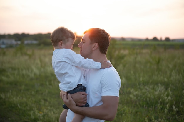 Vaderdag Vader en zoon samen buiten spelen op een zomer Gelukkige familie vader zoon bij zonsondergang