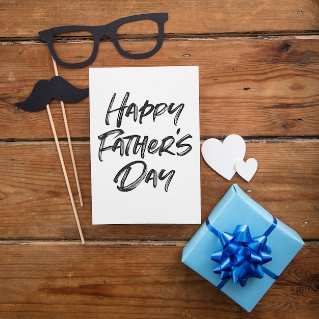 Vaderdagkaart met blauw ingepakt cadeau en papieren snor